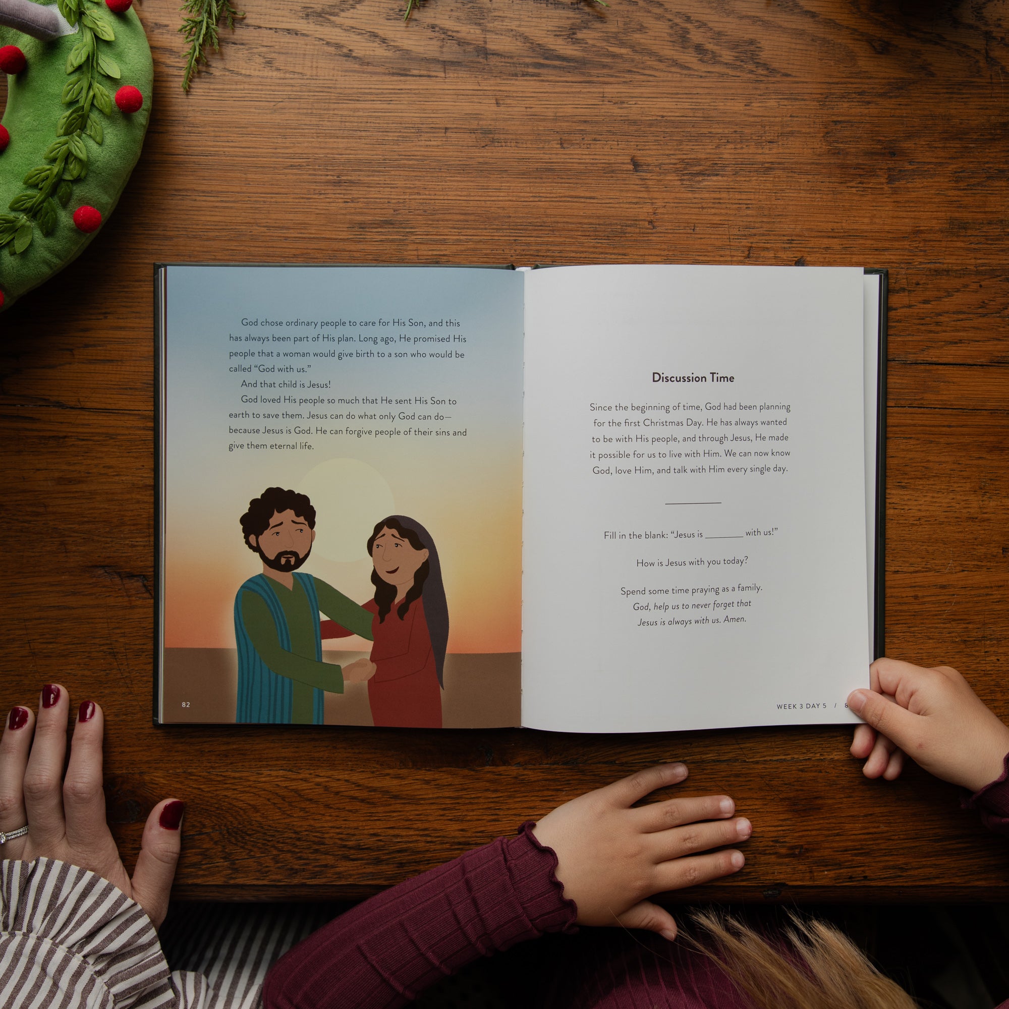 An open children's Bible book displayed on a wooden table, with two children's hands holding the pages and another hand resting nearby. The left page features a colorful illustration of a man and a woman, while the right page contains text under the heading 'Discussion Time.'