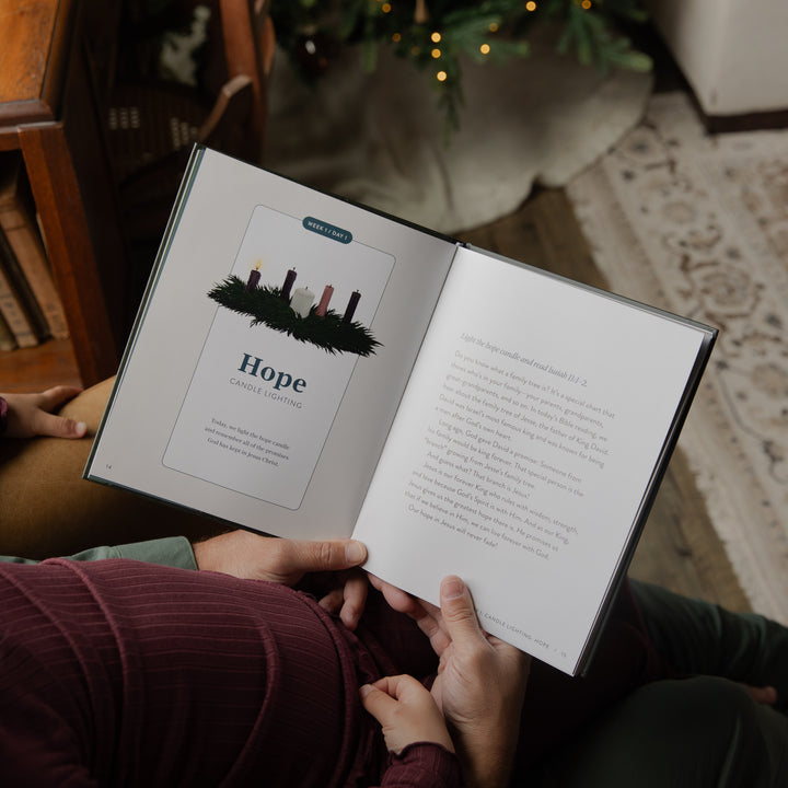 An open book titled 'Hope: Great Expectations' being held by hands in a cozy indoor setting, with a Christmas tree and warm lights blurred in the background.