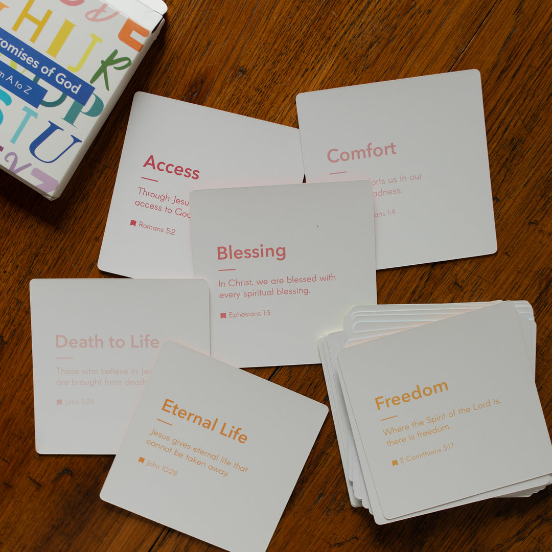 The backs of multiple Promises of God Verse Card set spread out on a wooden table