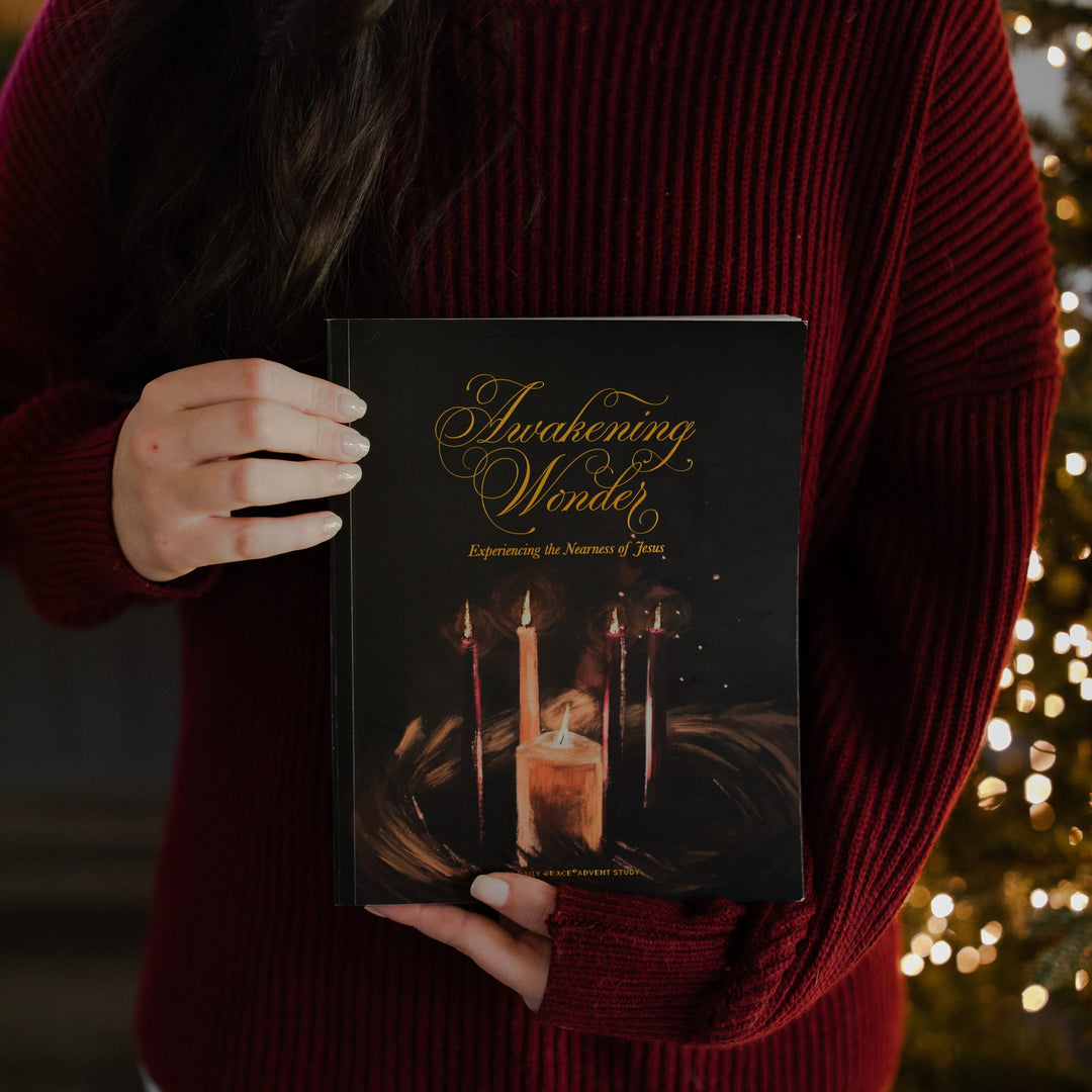 A woman standing holding the Awakening Wonder study facing the camera
