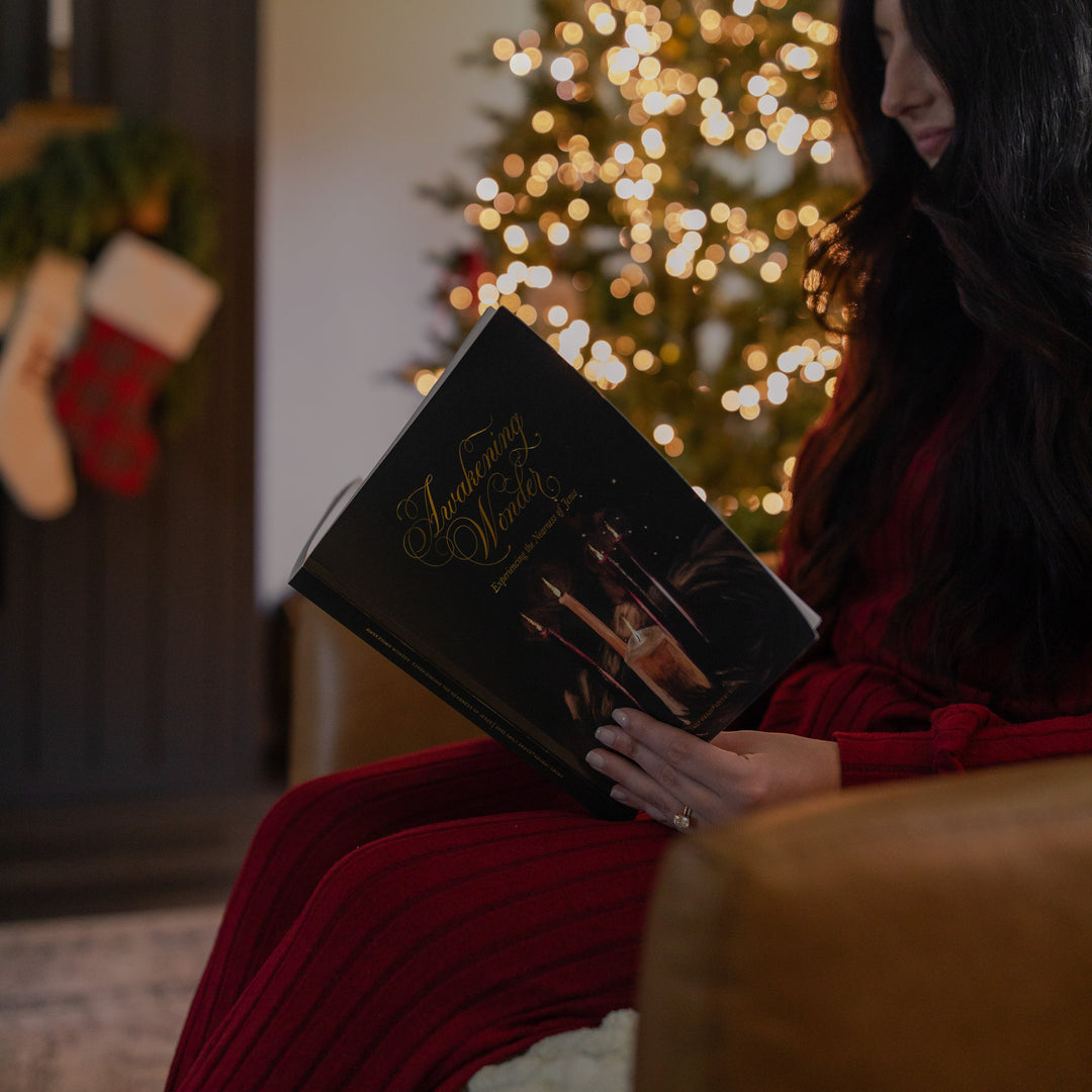 A woman reading the Awakening Wonder Study with a Christmas tree in the background