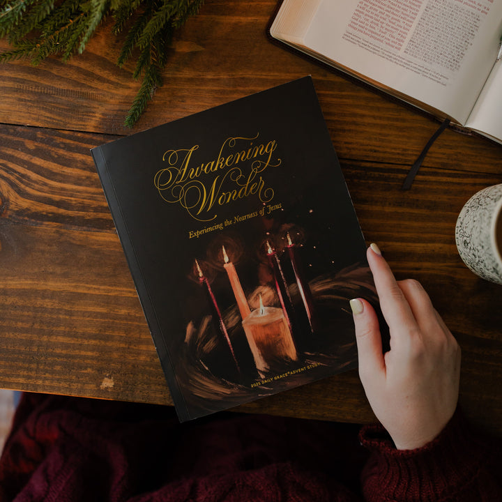 The Awakening Wonder cover with a woman's hand on the edge of the cover near an open bible