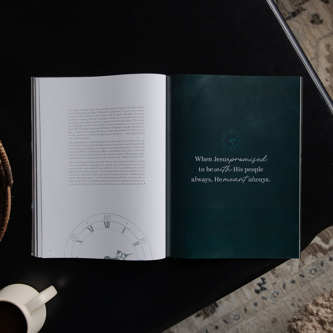 An open book laid flat on a dark surface, showing a white left page with dense text and a clock illustration near the bottom, and a dark teal right page with a quote in white script. A white mug is partially visible at the lower left, and a patterned rug appears at the lower right.
