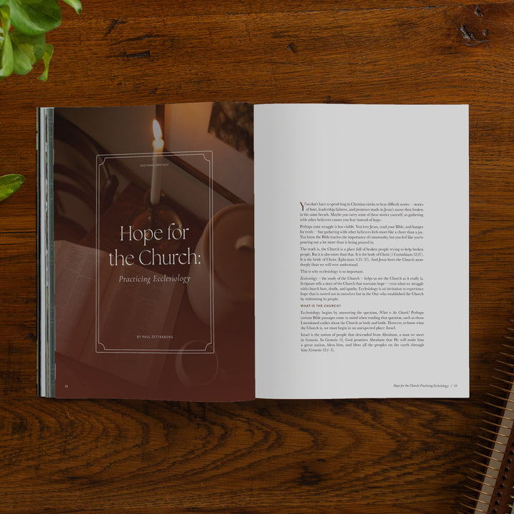 An open printed magazine spread laid on a wooden table. The left page has a large brown-toned photo with a lit candle and the title 'Hope for the Church.