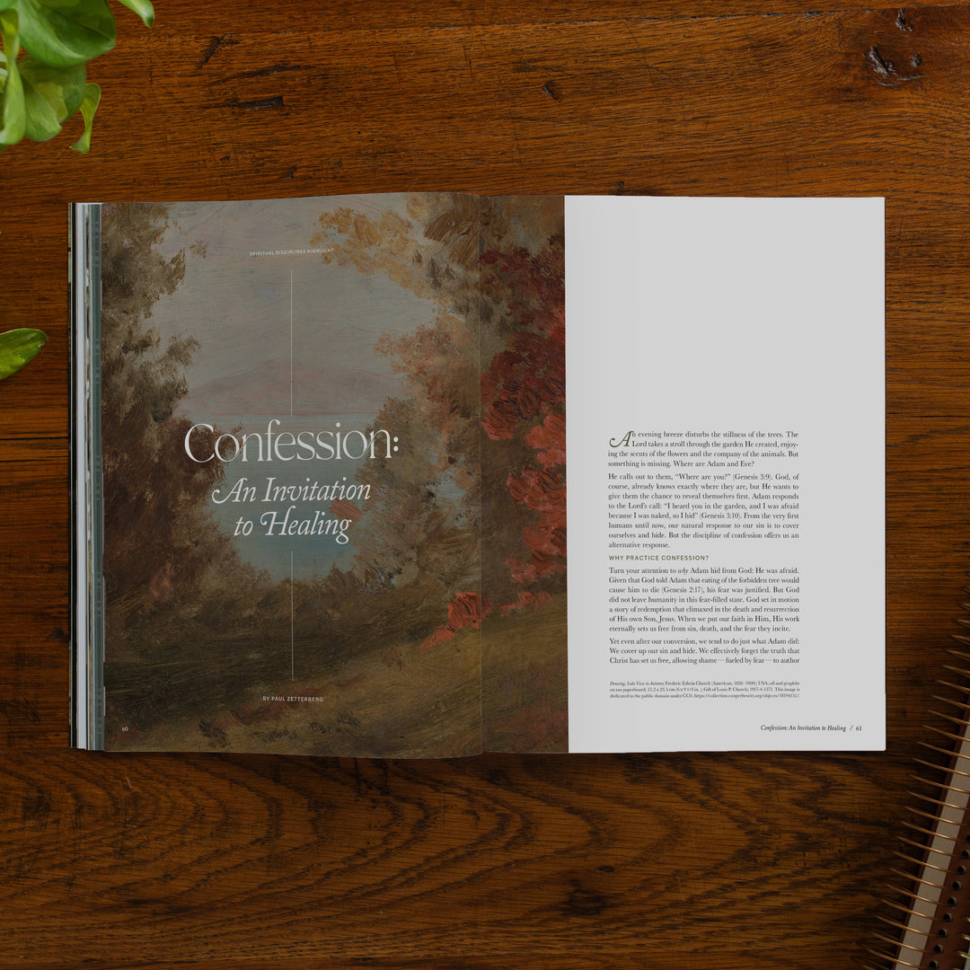 An open magazine spread titled "Confession: An Invitation to Healing" lies on a dark wooden tabletop. The left page features a muted landscape painting with trees and red foliage, while the right page contains a column of small text.
