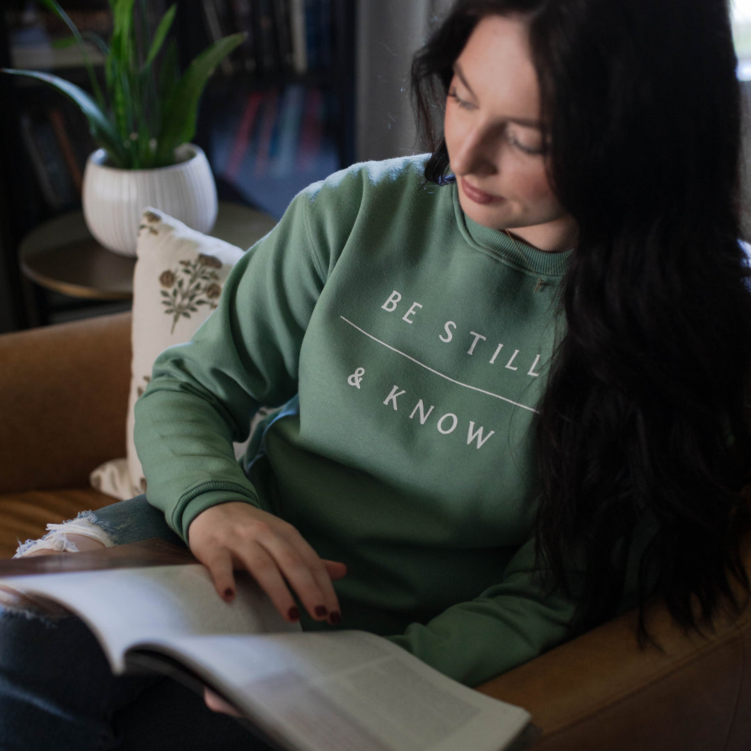 Woman wearing green be still and know christian sweatshirt