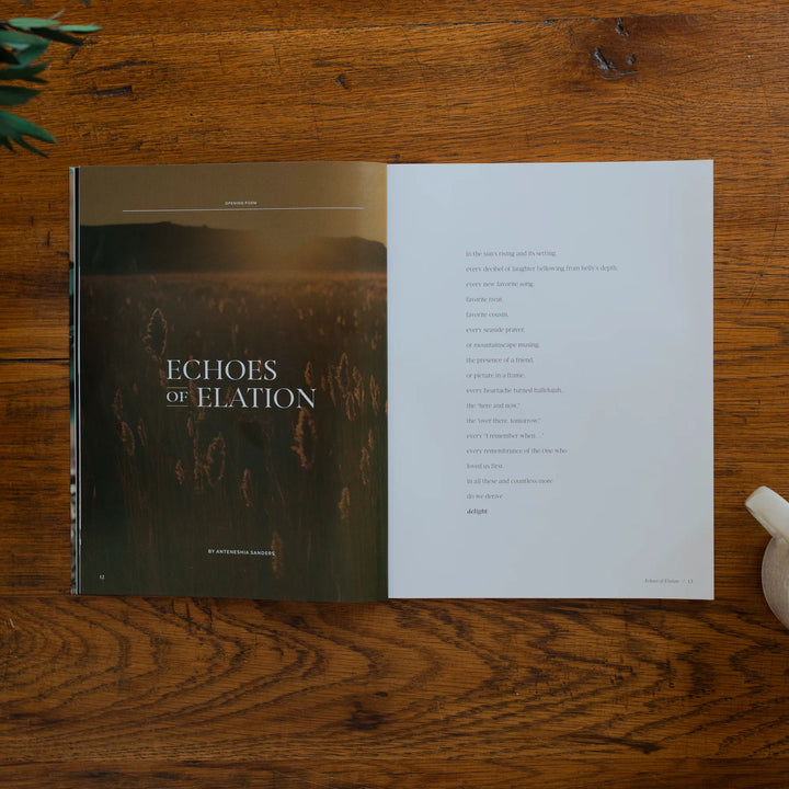 Be Still Magazine Issue 39 opened to the echoes of elation on a wooden table next to a coffee cup