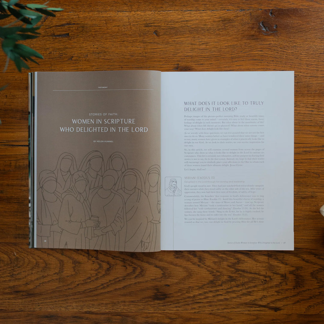 Be Still Magazine Issue 39 opened to the Women in Scripture page on a wooden table next to a coffee cup