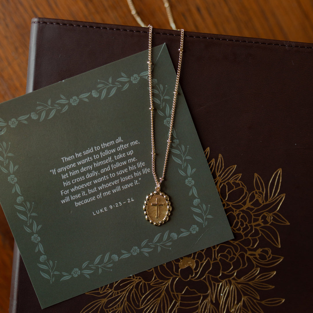 A beaded cross necklace on a verse card on a journal