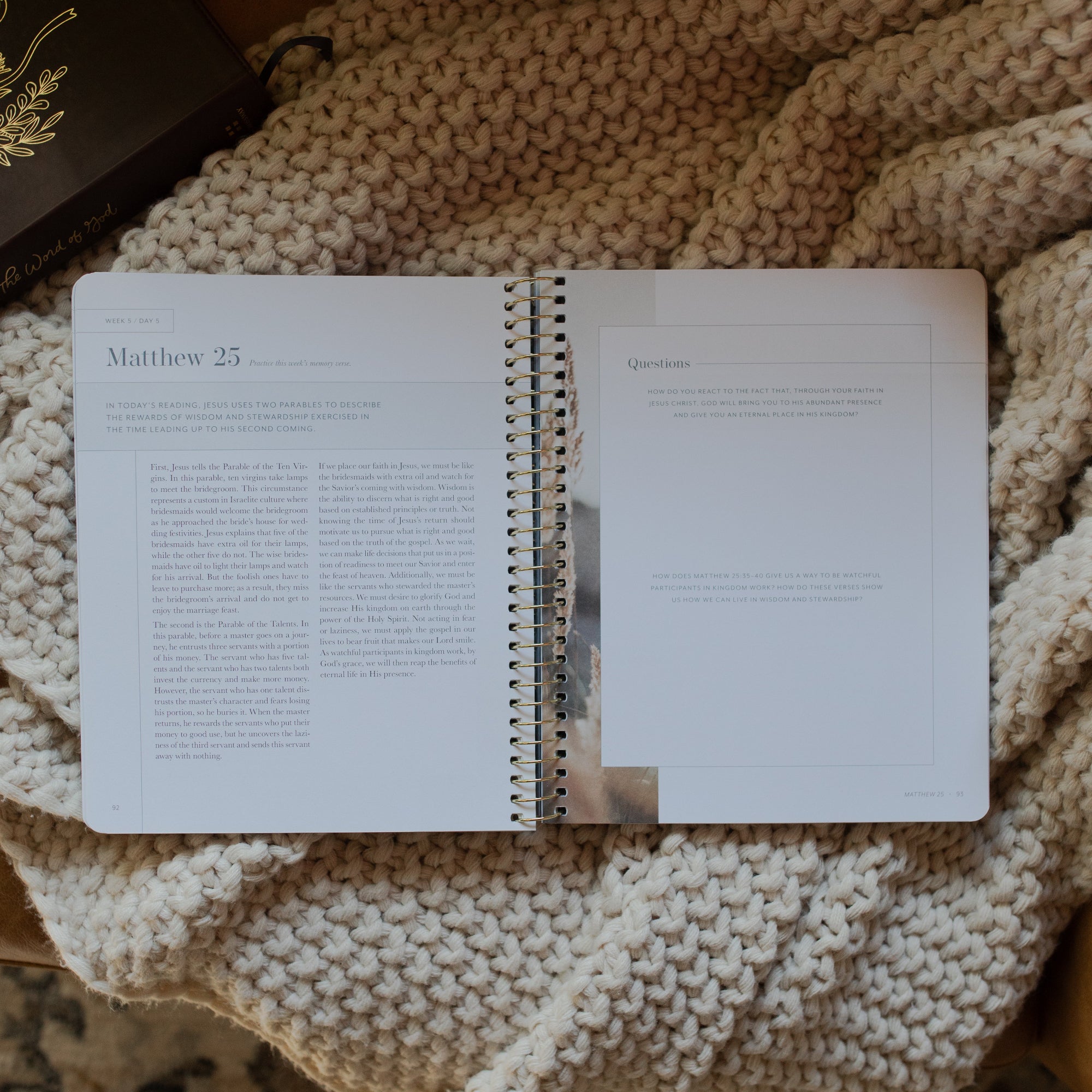 Behold Volume 1 Spiral Study opened to the Matthew 25 page on a knitted blanket next to a bible