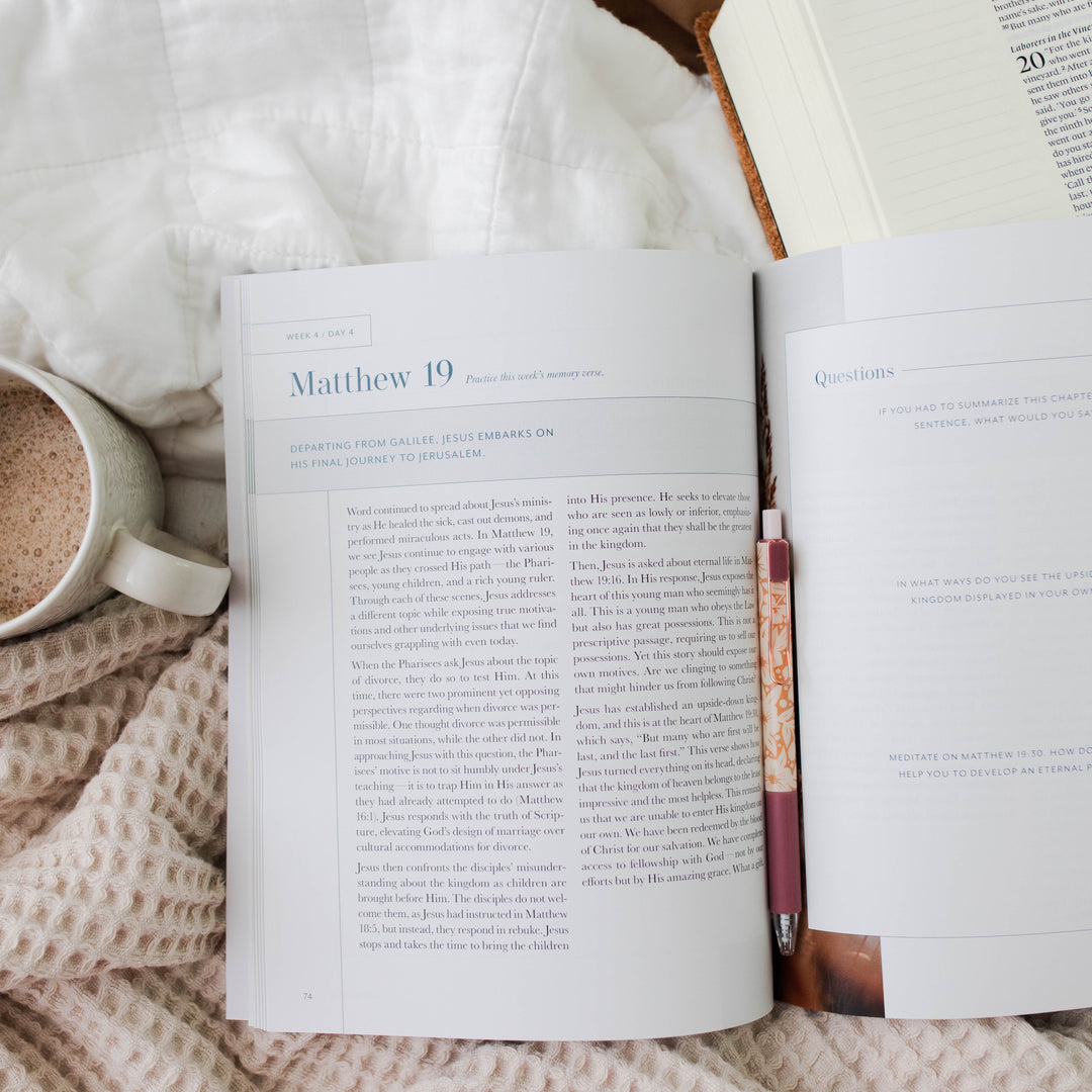 Open book with a pen and mug on a textured surface