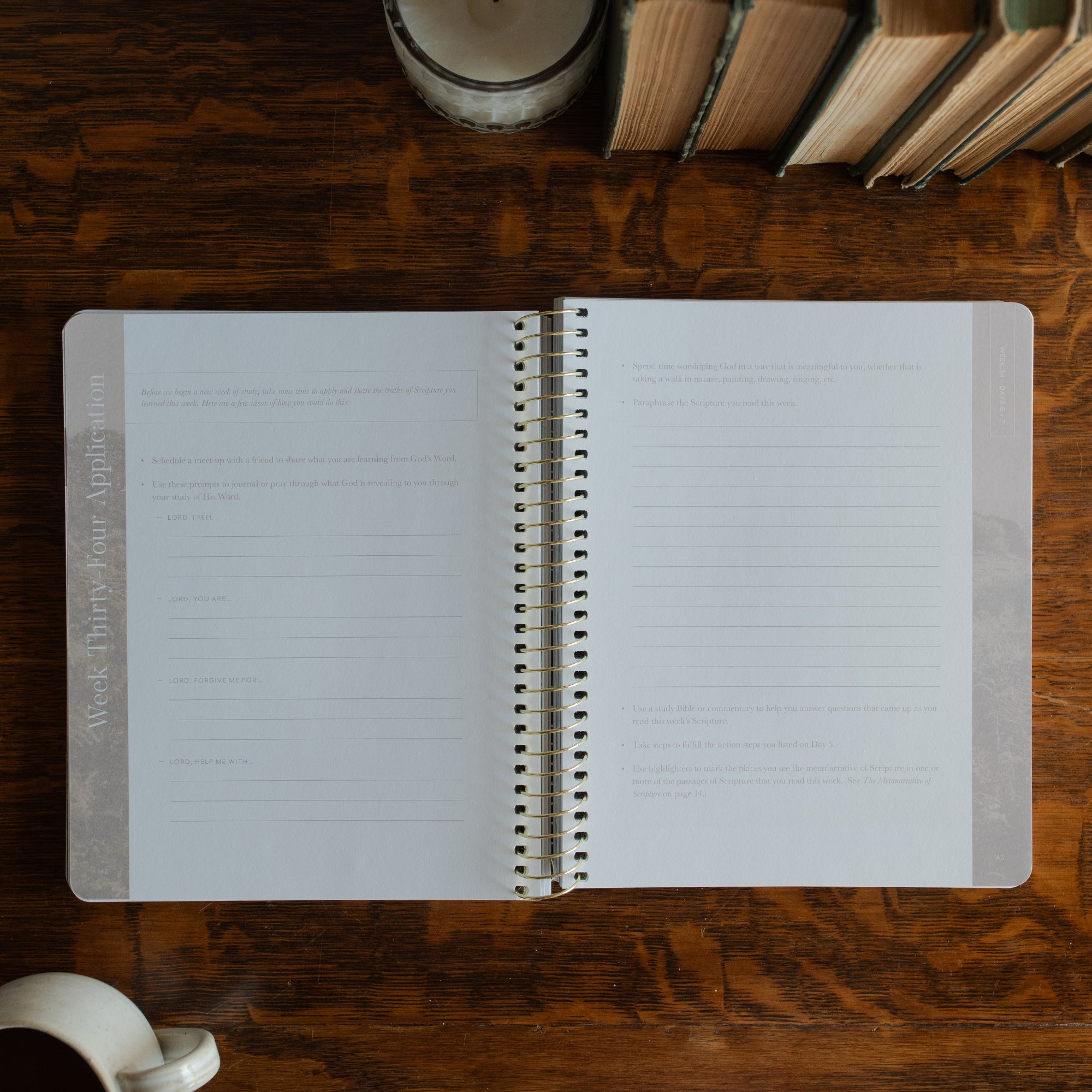 Behold Spiral opened to the applications page on a wooden table next to a coffee cup and some books