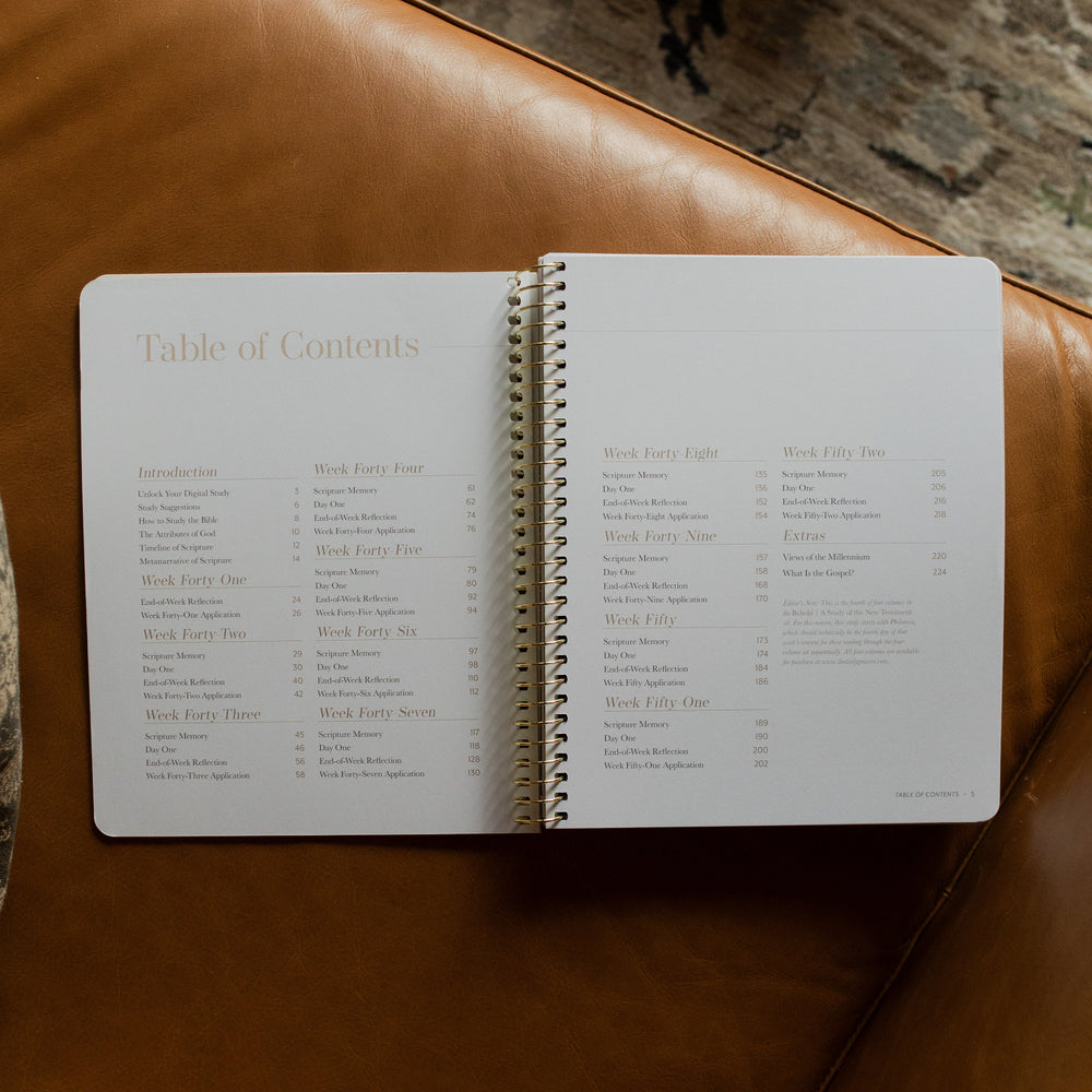 Behold Spiral Study opened to the table of contents page on a leather couch