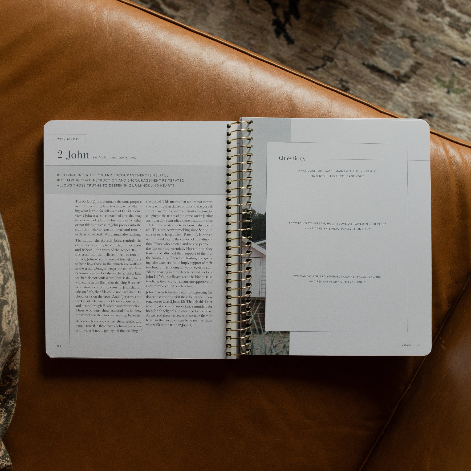 Behold Spiral Study opened to the questions page on a leather couch