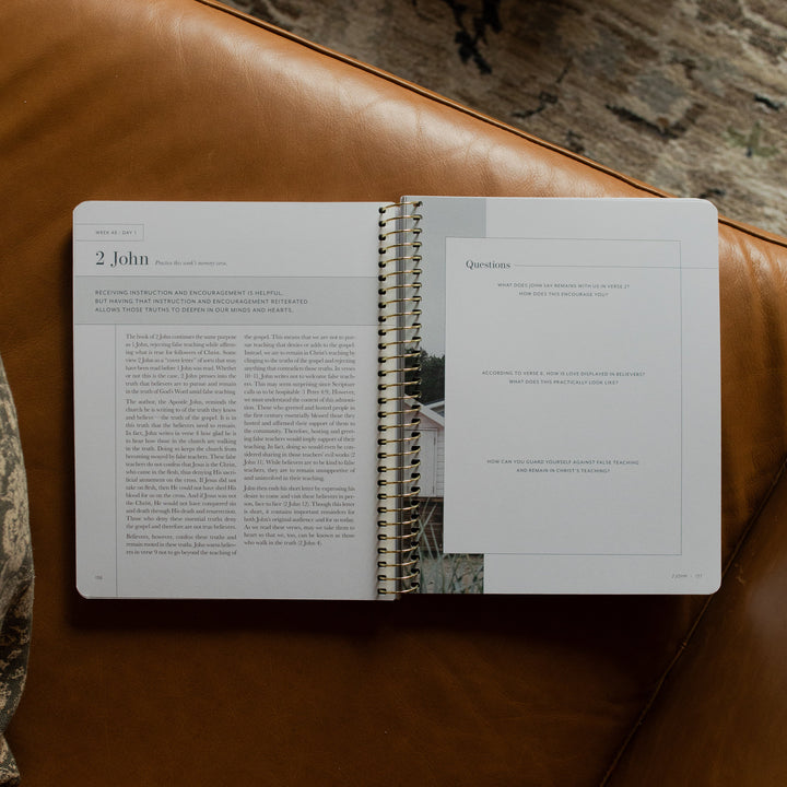 Behold Spiral Study opened to the questions page on a leather couch