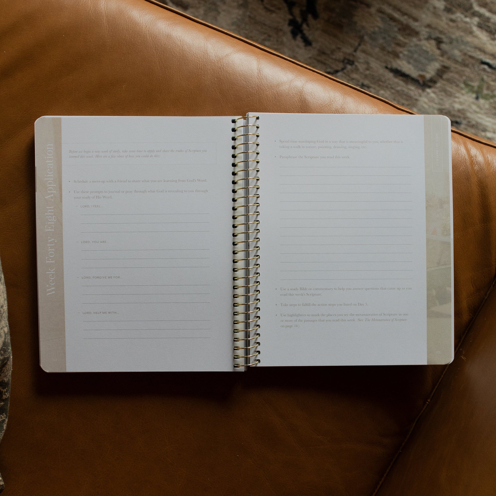 Behold Spiral Study opened to the week forty eight application page on a leather couch