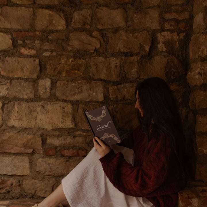 A woman reading the Beloved How Belonging to Jesus Secures your Identity near a brick wall