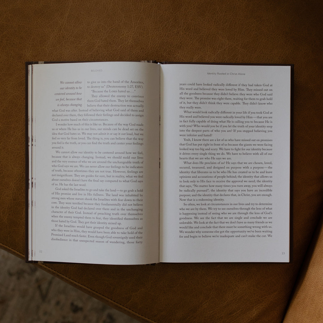 The Beloved How Belonging to Jesus Secures your Identity book opened to the Identity Rooted in Christ Alone middle of page resting on a brown leather couch