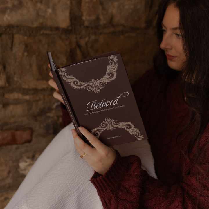 A woman reading the Beloved How Belonging to Jesus Secures your Identity close up near a brick wall