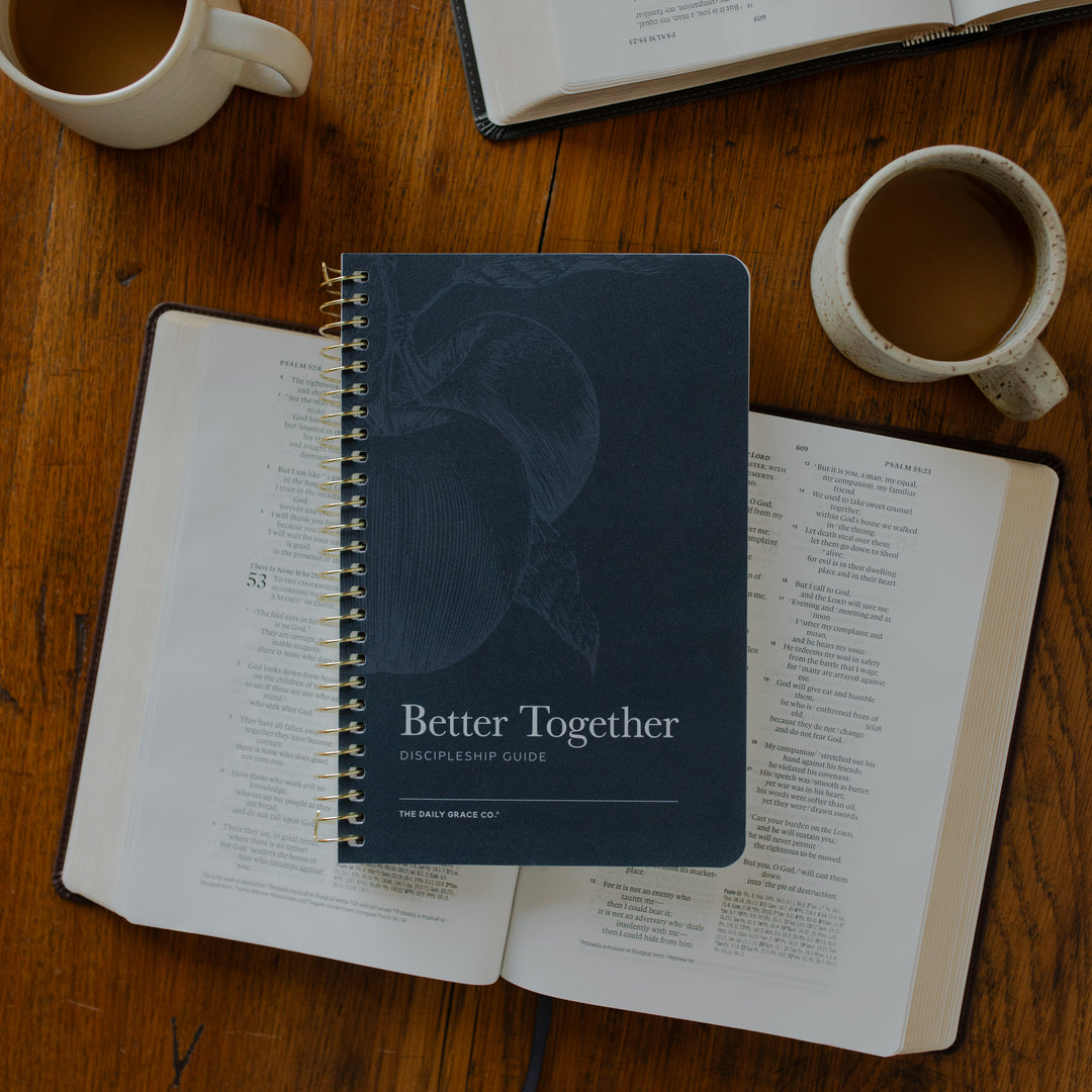 The Better Together Discipleship Guide on an open bible on a wooden table near a white coffee cup