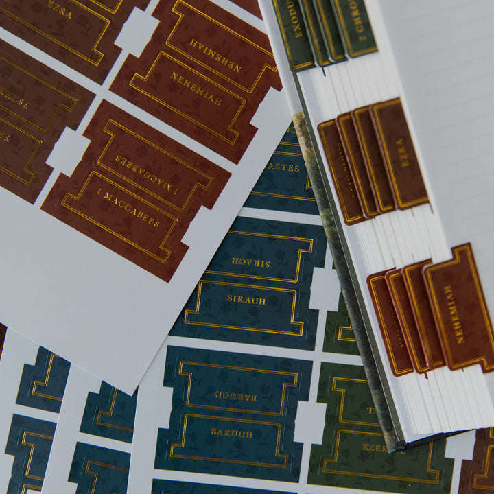 A close-up of a Bible study or sermon tracker sheet with tabs labeled by chapter and verse references, alongside a stack of matching brown and gold tabs on a white background.