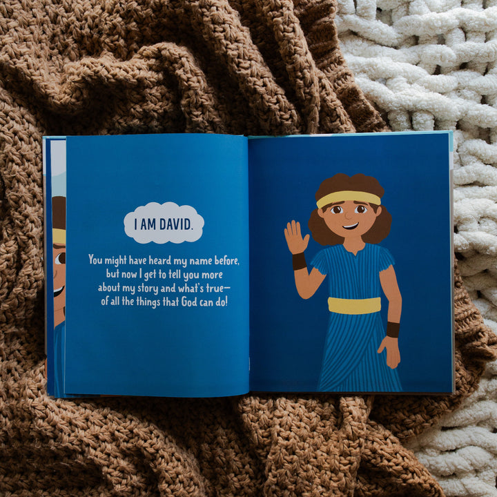 Brave in the Battle book opened to the I am David reveal page laying on a brown knitted blanket and a white knitted blanket