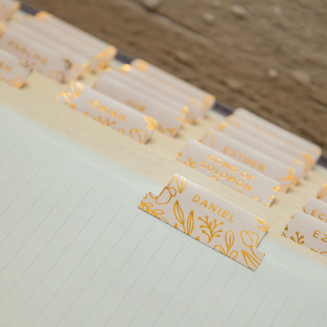 Gold-foil bookmarks on a notebook with names printed on them.