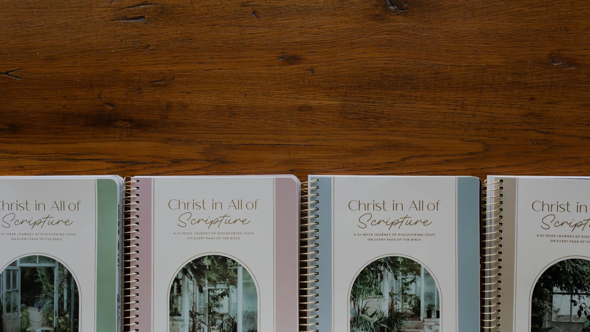 Three notebooks displaying the name "Chris" written in mud on their covers, arranged neatly on a flat surface.