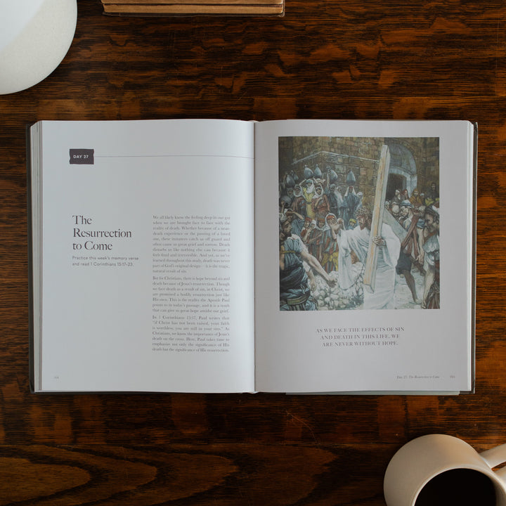 Clinging to the Cross Spiral hardcover opened to the resurrection to come page on a wooden table next to a coffee cup