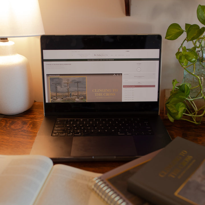 Clinging to the Cross loaded on a computer near two closed Clinging to the Cross studies and an open bible