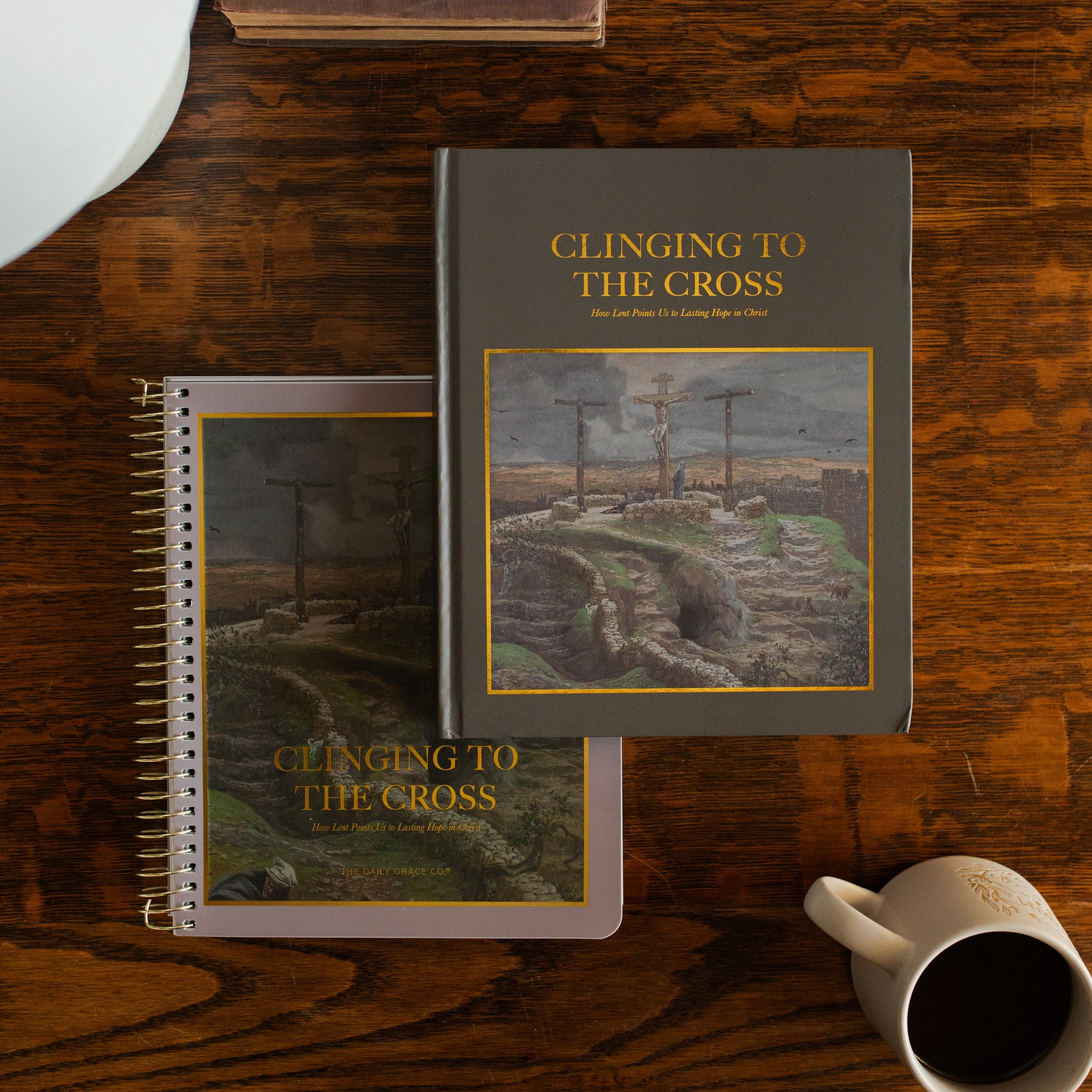 Both of the Clinging to the Cross studies on a wooden table near a coffee cup