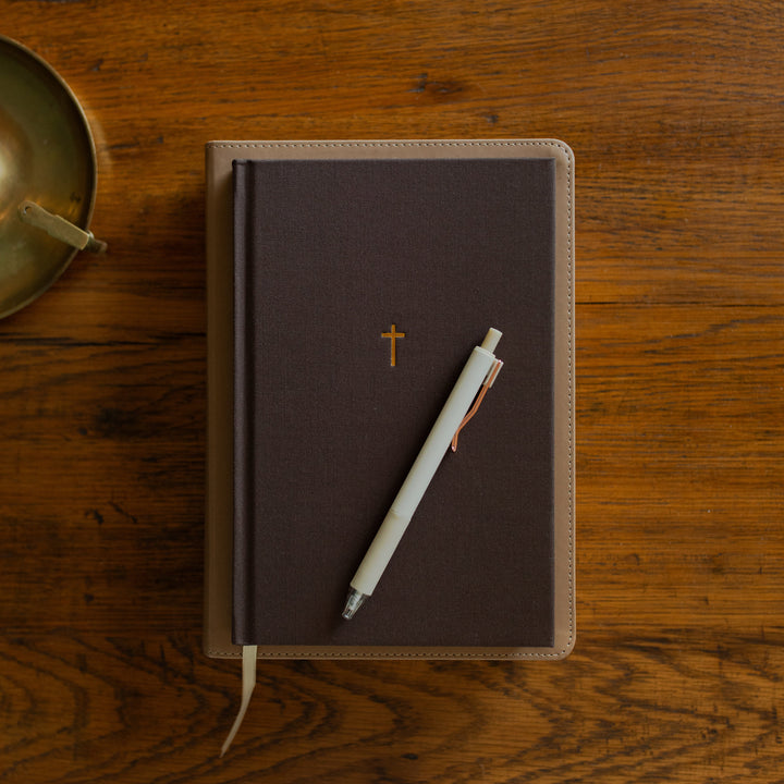 The Cross Journal cover on a bible on a wooden table