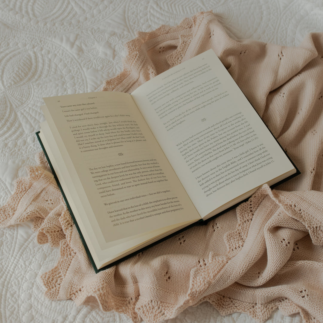 The Daily Grace Hardcover book opened to a reading portion page on some white sheets