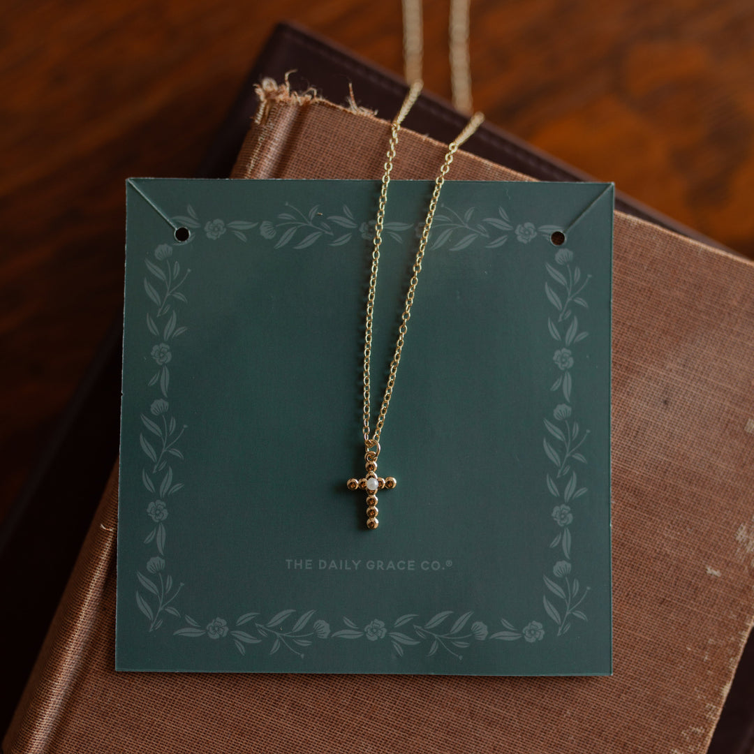 A dainty cross necklace on multiple journals