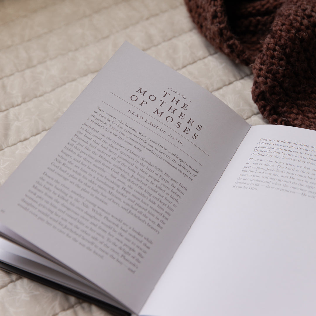 Open book with the page titled 'The Mothers of Moses' on a textured surface with a brown knitted item.