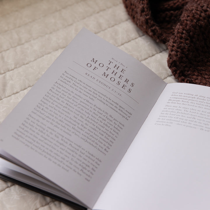 Open book with the page titled 'The Mothers of Moses' on a textured surface with a brown knitted item.