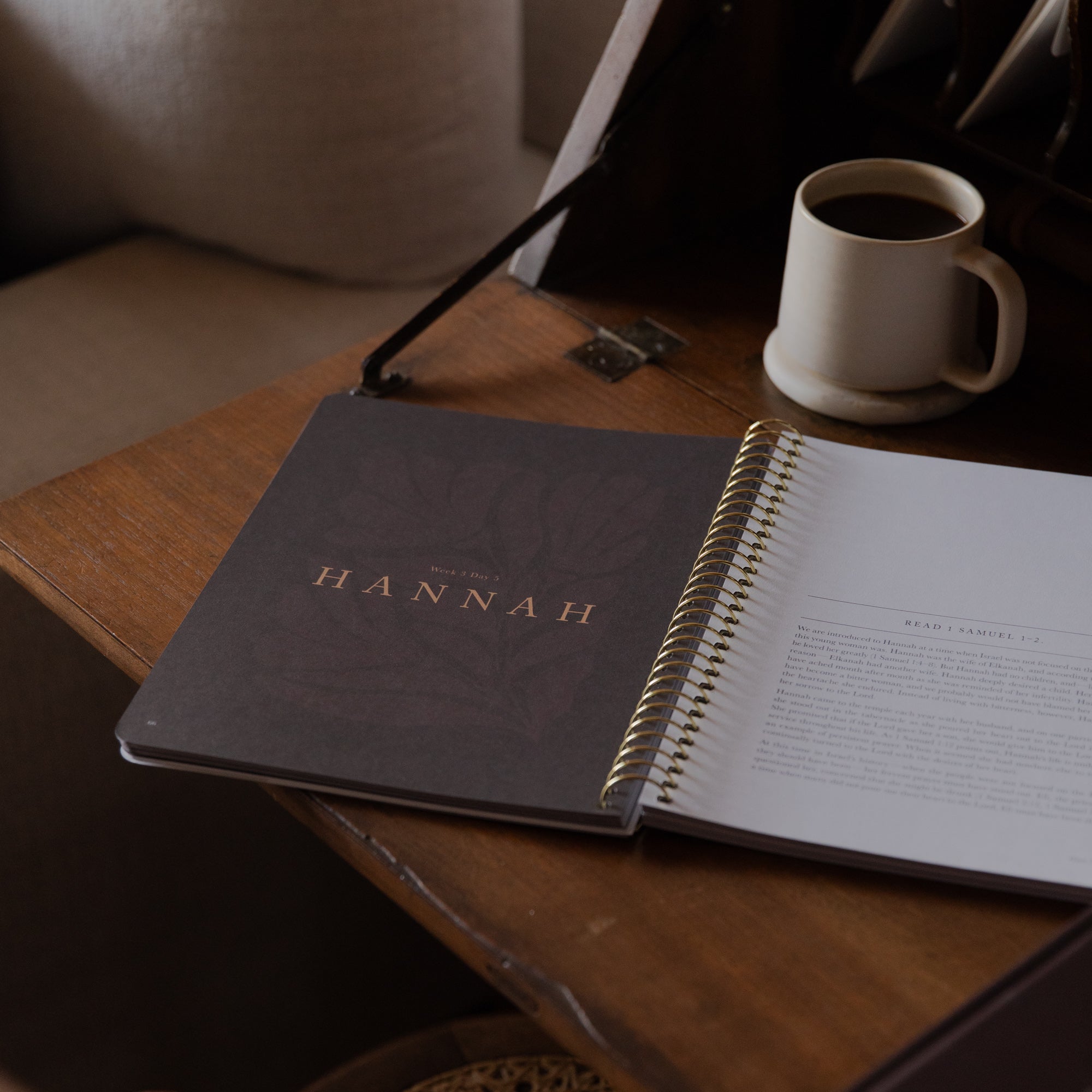 Open bible study with 'HANNAH' on the cover next to a cup of coffee on a wooden table.
