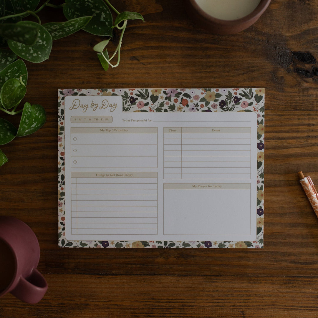 Day by Day Magnolia Floral Notepad sitting on a wood table