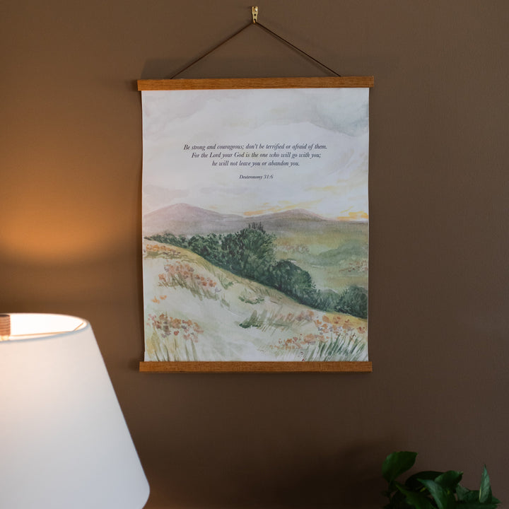 Field Watercolor Hanging Canvas hanging on a brown wall next to a lampshade