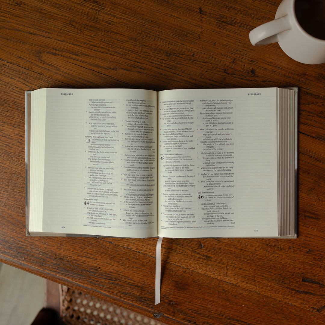 ESV Journaling Good Shepherd Bible opened to Psalms on a wooden table next to a white coffee cup