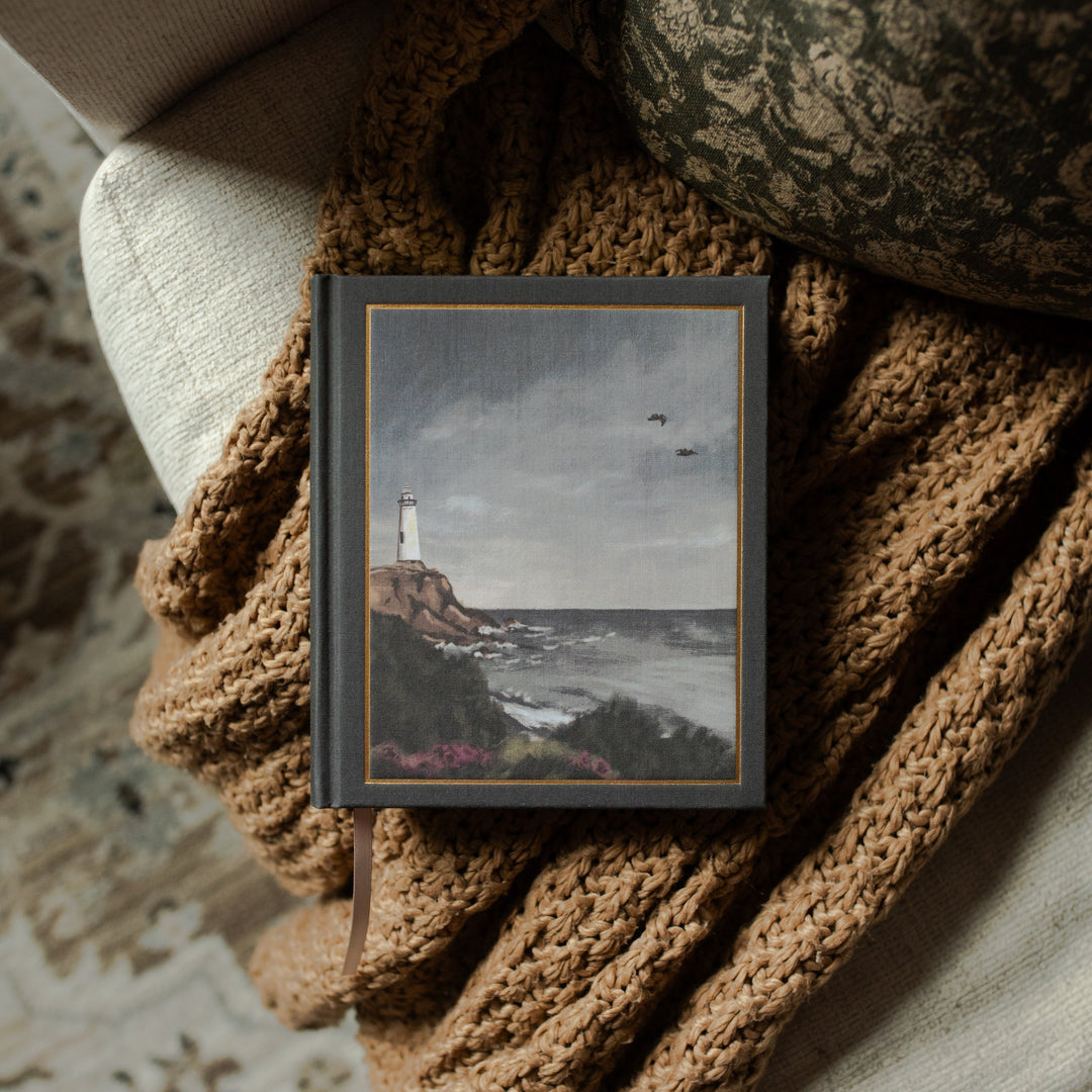 ESV Journaling Lighthouse Bible on the cover on a woven blanket and a white couch