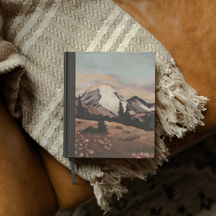 ESV Journaling Bible with mountains on the cover on a woven blanket and a leather couch