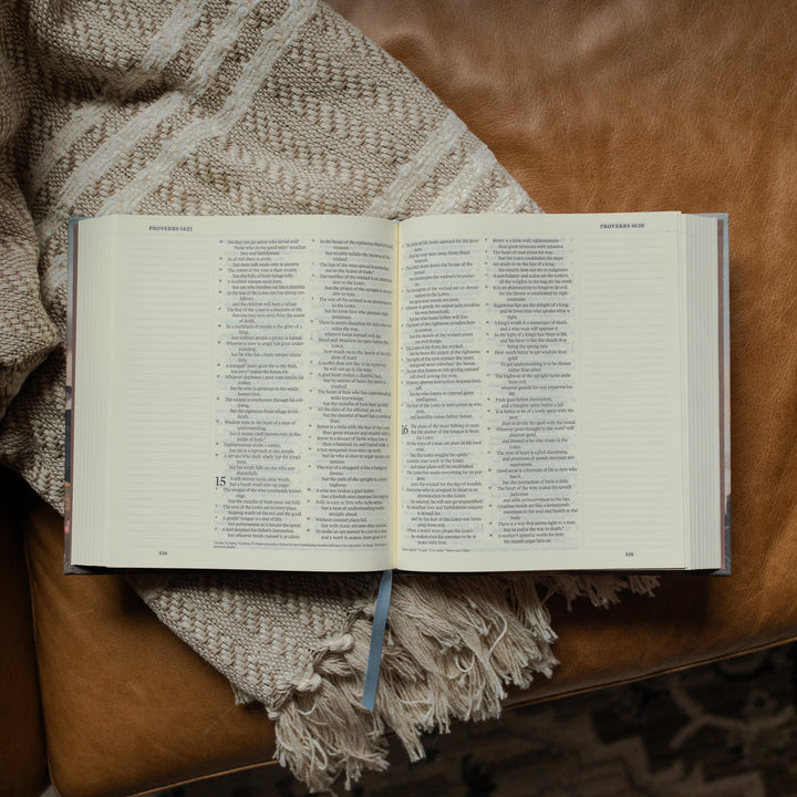 ESV Journaling Mountains Bible opened to the Proverbs section on a blanket on a leather couch