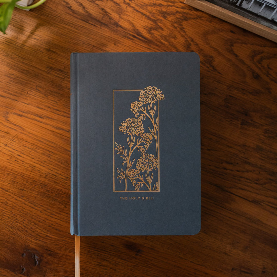 Blue Bible with gold flower design on table