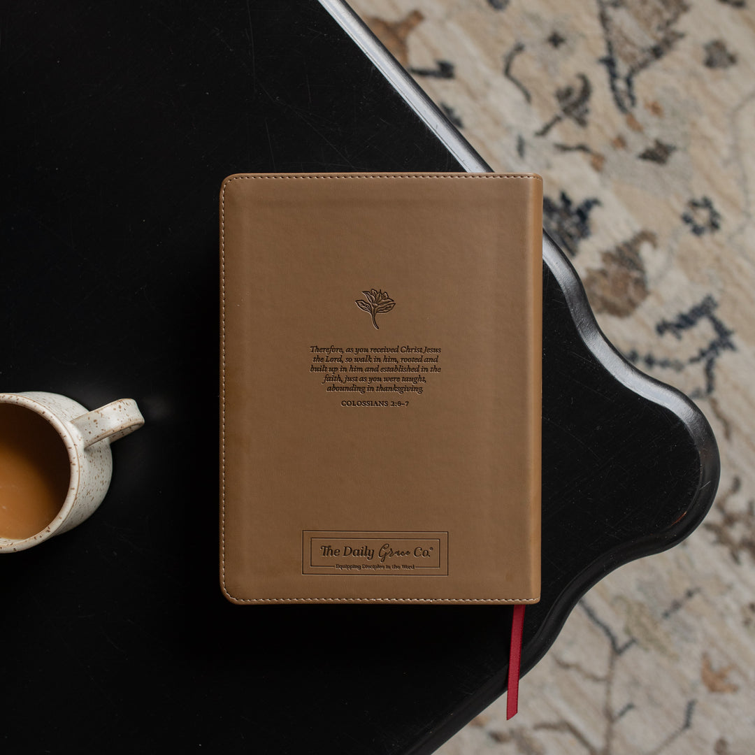 The back of the ESV Single Column Journaling Bible on a black wooden table near a coffee cup