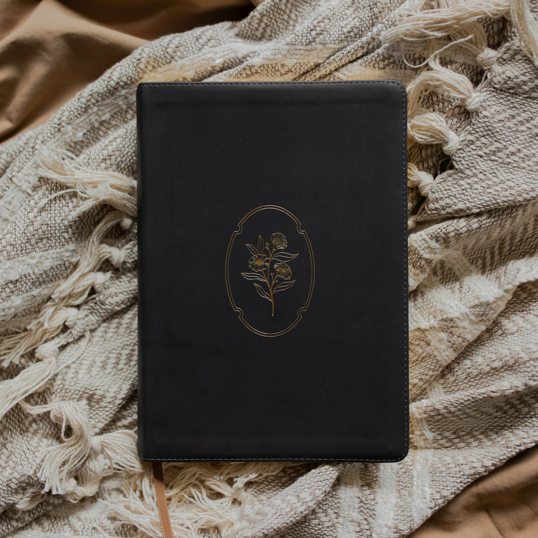 Black bible with gold engraved cover on a textured blanket