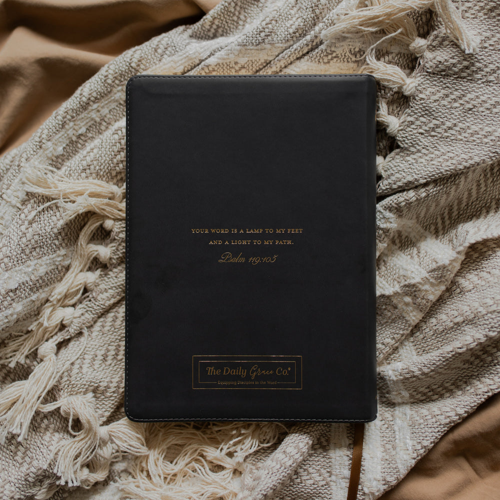 Black bible with gold engraving back cover on a textured blanket