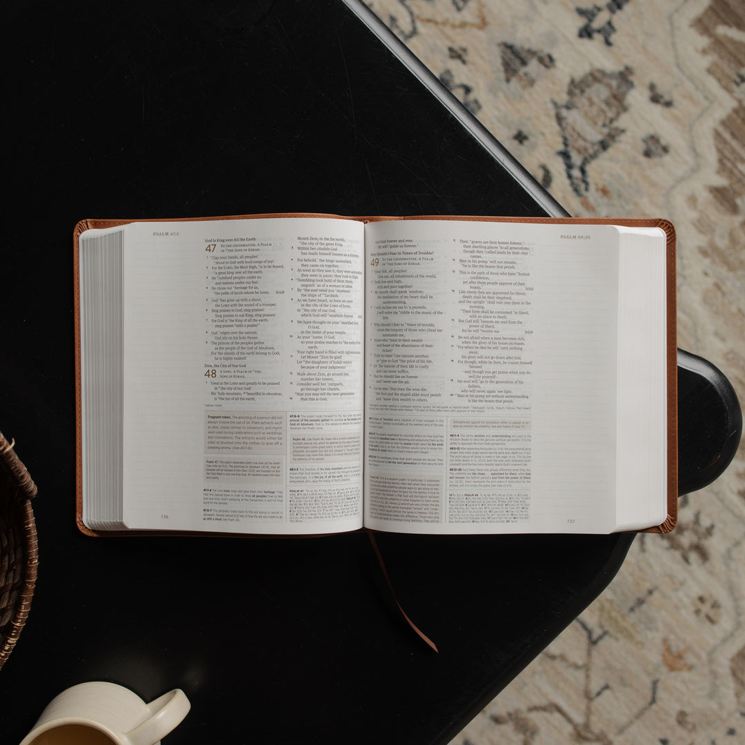 A leather ESV bible opened to the Psalms pages on a dark wooden table