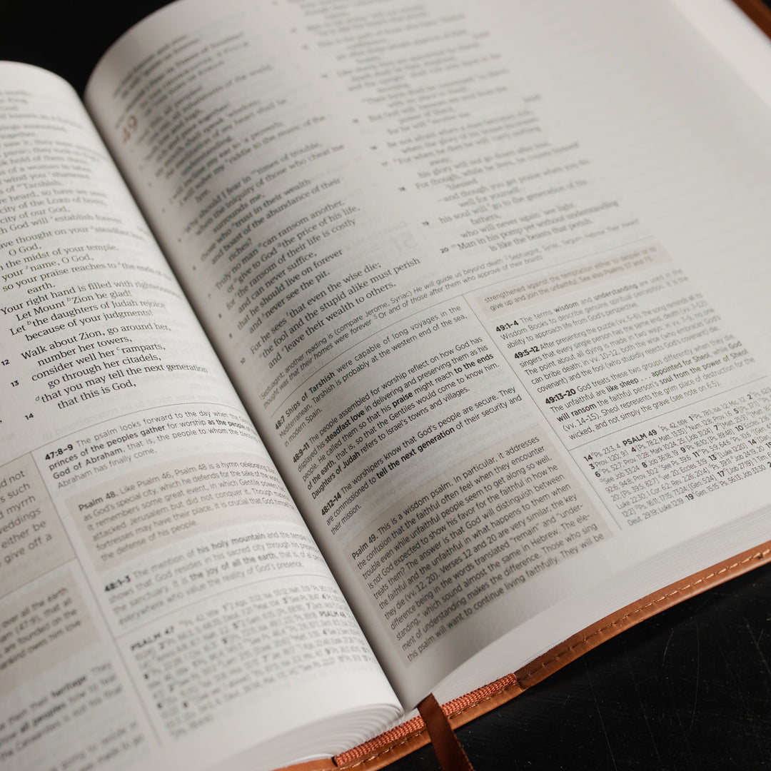 Up close of A leather ESV bible opened to the Psalms pages on a dark wooden table