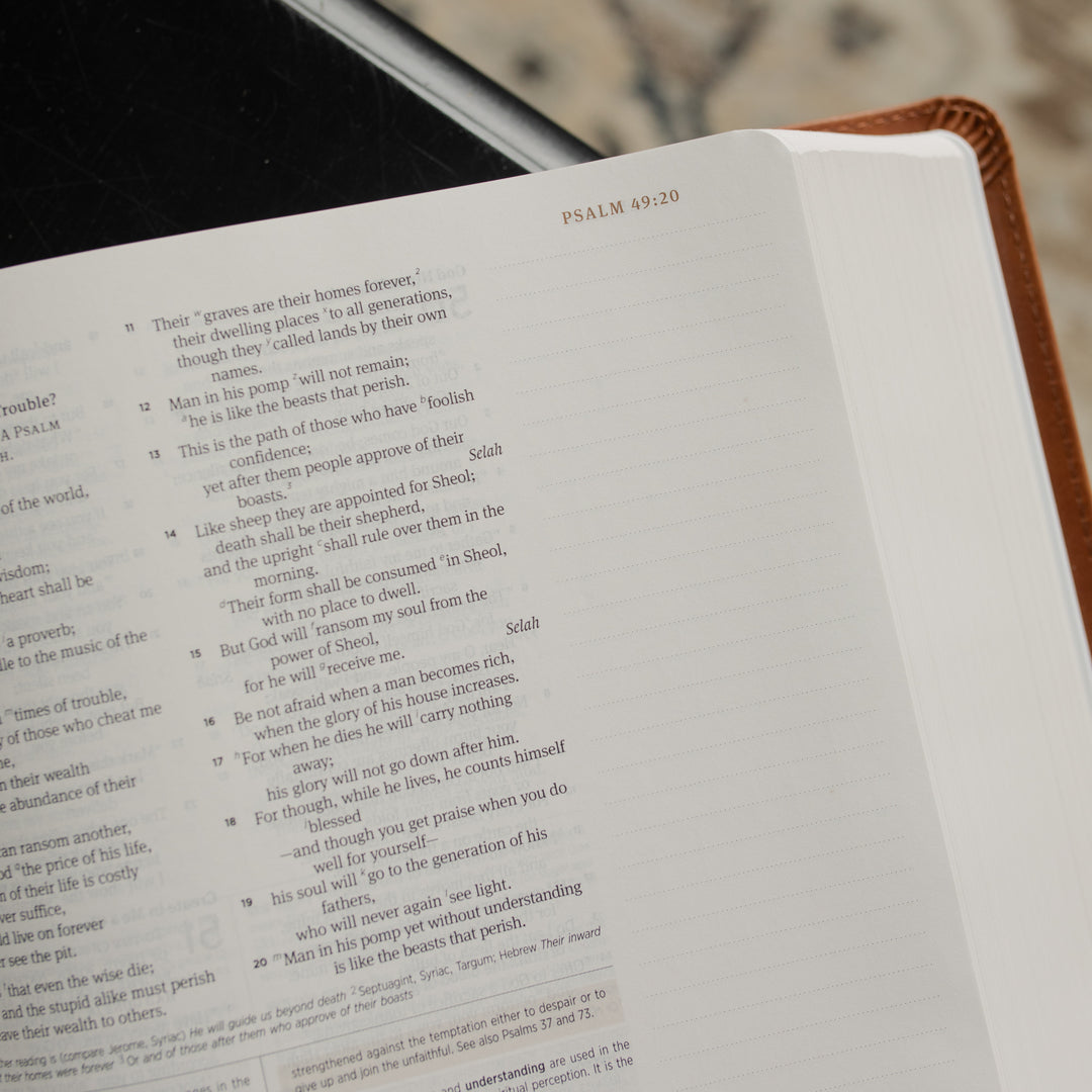 Up close of A leather ESV bible opened to the corner of the Psalms pages on a dark wooden table